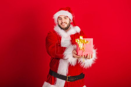 Téléchargez les photos : Blanc, Brésilien habillé en tenue de Noël, Père Noël. tenant cadeau rouge. - en image libre de droit