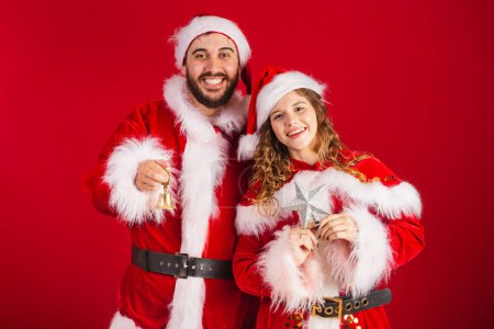 Téléchargez les photos : Couple brésilien, habillé en vêtements de Noël, Père Noël, tenant des décorations de Noël, étoile, cloche. - en image libre de droit