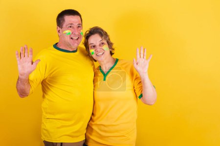 Photo for Adult couple, soccer fans from brazil isolated on yellow - Royalty Free Image