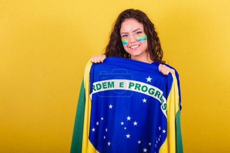 Photo for Woman soccer fan, fan of brazil, world cup, holding flag and displaying order and progress. - Royalty Free Image