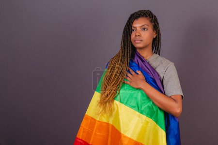 Foto de Joven mujer afrobrasileña, bandera LGBT, LGBTQ, bisexual. diversidad. Lesbianas. Mano en el pecho para mostrar sus valores para la causa - Imagen libre de derechos