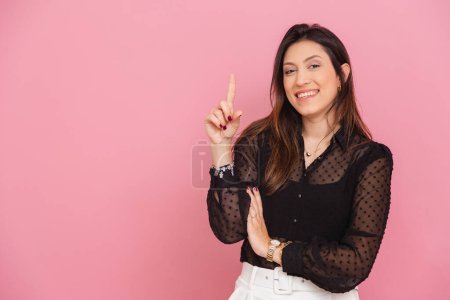 Foto de Hermosa mujer brasileña caucásica, fondo rosa, con el dedo levantado que sugiere la idea, pregunta y sugerencia, empresario. - Imagen libre de derechos
