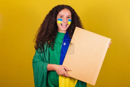 Photo for Brazilian caucasian girl soccer fan holding sign for announcement, text, advertisement. World Cup. Olympics. - Royalty Free Image