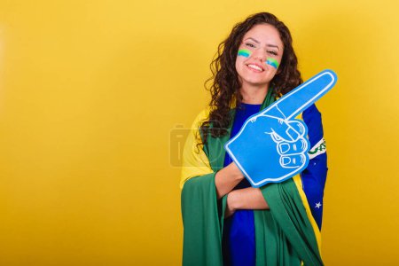 Téléchargez les photos : Femme fan de football, fan de brésil, coupe du monde, portant un gant en mousse. bras croisés, souriants, confiants. - en image libre de droit