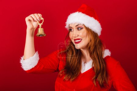 Foto de Hermosa brasileña pelirroja, vestida con ropa de Navidad, Santa Claus. usando la campana de Navidad. - Imagen libre de derechos