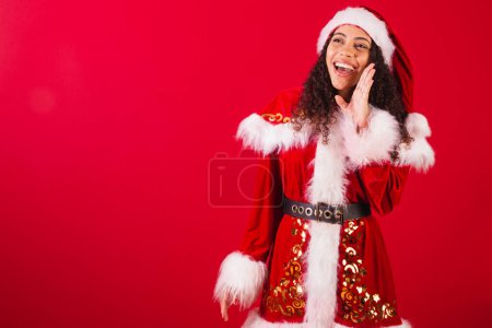 Foto de Hermosa mujer negra brasileña, vestida como santa claus, ropa de Navidad. promoción gritando. - Imagen libre de derechos