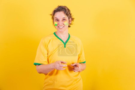 Photo for Adult adult woman, brazil soccer fan, pointing at screen, choosing you. - Royalty Free Image