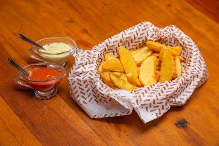 Photo for Rustic French fries, a typical Brazilian snack, served with mayonnaise and chili sauce. - Royalty Free Image