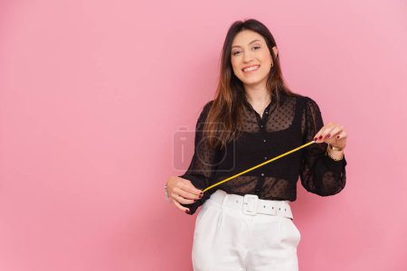Photo for Beautiful Brazilian Caucasian Woman, Pink Background, Holding Tape Measure, Nutritionist, Aesthetics, Measures, Quality of Life and Health. - Royalty Free Image