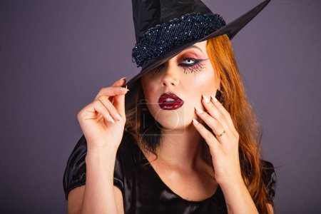 Foto de Ensayo de Halloween, mujer caucásica con disfraz de bruja. primer plano retrato sosteniendo sombrero y las manos en la cara - Imagen libre de derechos