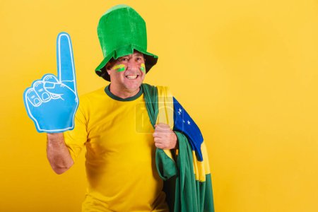 Photo for Adult man, soccer fan from brazil, wearing flag, with foam finger smiling for photo. - Royalty Free Image
