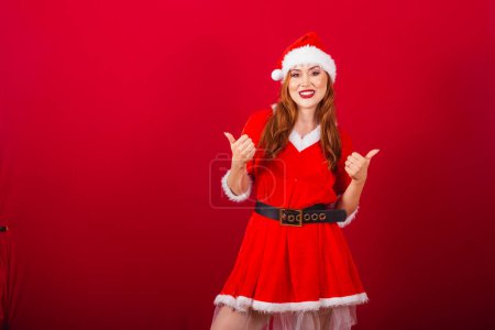 Photo for Beautiful Brazilian red-haired woman, dressed in Christmas clothes, Santa Claus. like, positive, thumbs up. - Royalty Free Image