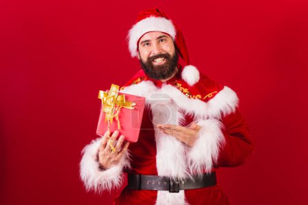 Photo for Brazilian santa claus young caucasian man. holding red gift. - Royalty Free Image