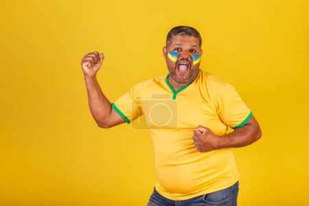 Foto de Hombre negro brasileño, fanático del fútbol de Brasil. celebrando, celebrando. - Imagen libre de derechos