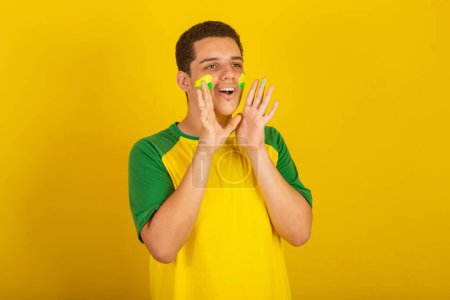 Foto de Joven aficionado al fútbol brasileño. vestido de verde, y amarillo, meta gritando - Imagen libre de derechos