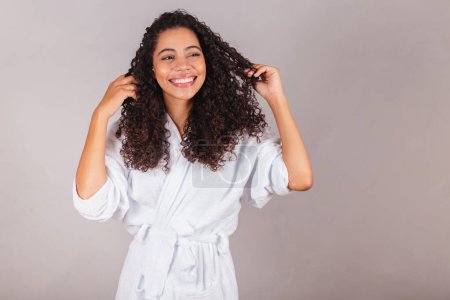 Foto de Mujer brasileña negra, con albornoz y toalla. cabello rizado, spa, centro de belleza, cuidado del cabello. mostrando pelo. rizos. - Imagen libre de derechos