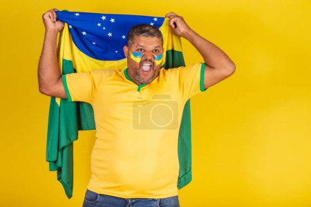 Photo for Brazilian black man, soccer fan from Brazil. vibrating the flag of Brazil on the back. - Royalty Free Image