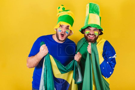 Foto de Dos amigos, brasileños, aficionados al fútbol de Brasil, vestidos para animar en un campeonato. - Imagen libre de derechos