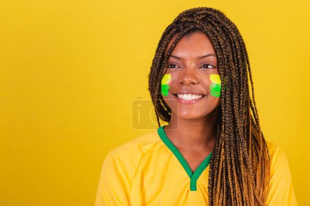 Foto de Mujer negra joven aficionada al fútbol brasileño. foto de cerca, sonriendo a la cámara, feliz. - Imagen libre de derechos