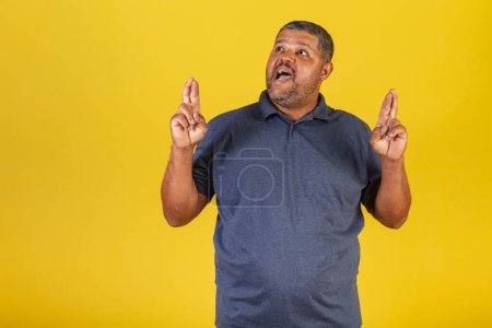 Foto de Hombre negro brasileño, adulto sonriendo, dedos cruzados, deseando, signo de suerte. - Imagen libre de derechos
