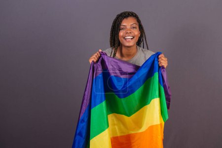 Photo for Young Afro Brazilian woman, LGBT flag, LGBTQ, bisexual. celebrating victory for the cause, diversity. - Royalty Free Image