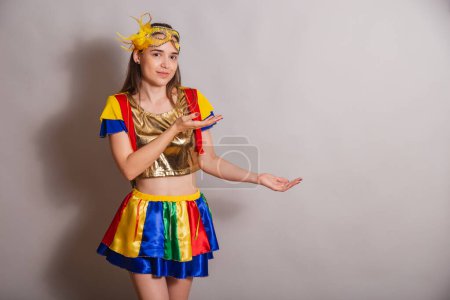 Photo for Beautiful Brazilian, Caucasian woman, wearing frevo, carnival clothes, wearing a mask. showing something to the right. - Royalty Free Image
