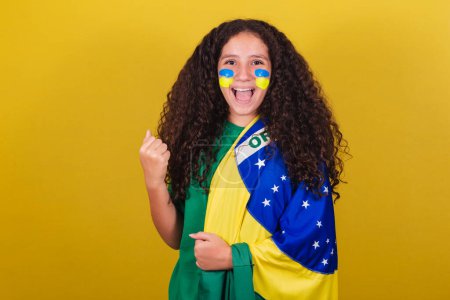 Photo for Brazilian caucasian girl, soccer fan, clenched fist, screaming yes, celebrating Brazil victory. - Royalty Free Image