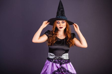 Foto de Ensayo de Halloween, mujer caucásica con disfraz de bruja. Con la mano en el sombrero. - Imagen libre de derechos
