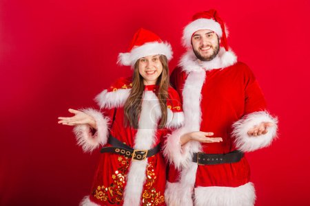 Photo for Brazilian couple with christmas clothes, santa claus. Welcome with open arms. - Royalty Free Image