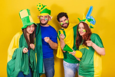 Téléchargez les photos : Groupe d'amis, fans de football brésilien, portant le drapeau brésilien, pointant vers la caméra, vous choisissant. - en image libre de droit