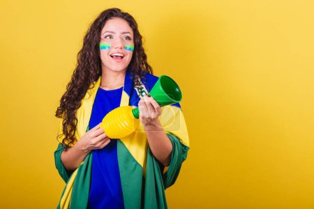 Téléchargez les photos : Femme fan de football, fan de brésil, coupe du monde, tenant corne, instrument sonore, faisant du bruit en acclamant. - en image libre de droit