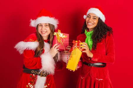 Foto de Dos amigos brasileños, vestidos con ropa de navidad, Papá Noel, intercambiando regalos de navidad. - Imagen libre de derechos