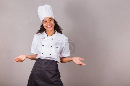 Téléchargez les photos : Jeune femme brésilienne noire, cuisinière, chef cuisinier. à bras ouverts, bienvenue. - en image libre de droit