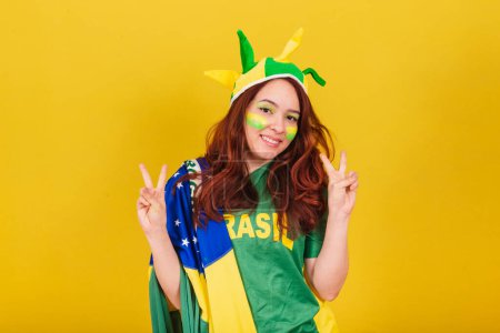 Photo for Caucasian, red-haired woman, soccer fan from Brazil, in peace and love pose. - Royalty Free Image