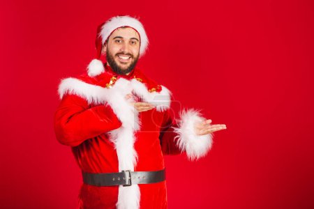 Photo for Brazilian man, dressed in santa claus clothes, presenting product or text on the right - Royalty Free Image
