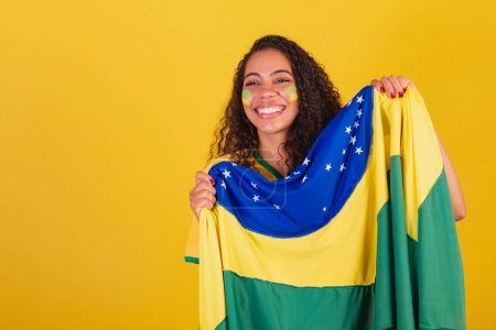 Foto de Joven brasileña negra, fanática del fútbol. con bandera de Brasil. animando y celebrando. - Imagen libre de derechos
