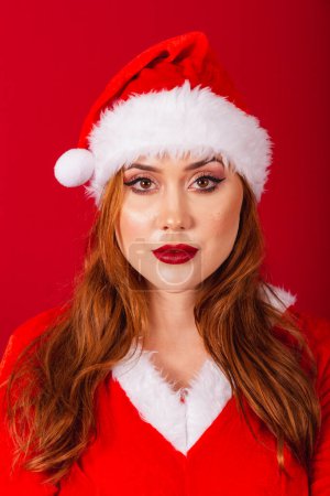 Photo for Beautiful Brazilian red-haired woman, dressed in Christmas clothes, Santa Claus. vertical close-up shots of the face, modeling for the camera. - Royalty Free Image