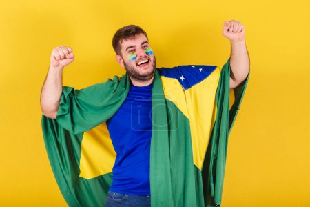 Téléchargez les photos : Homme caucasien brésilien, fan de football brésilien, célébrant, vibrant l'objectif de son équipe. - en image libre de droit