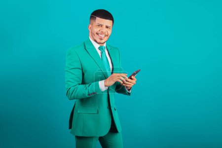 Foto de Hombre negro brasileño, vestido de traje y corbata verde, Empresario. usando smartphone - Imagen libre de derechos