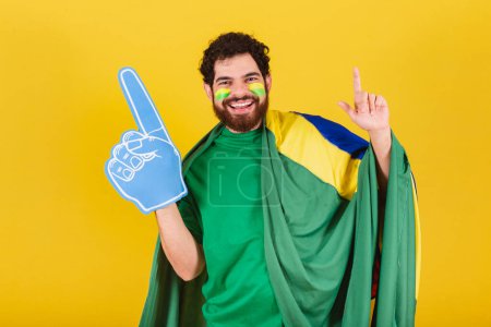 Photo for Man, brazilian, bearded, soccer fan from brazil, using foam finger doing dance choreography for team victory, goal. - Royalty Free Image