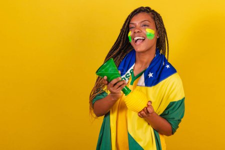 Téléchargez les photos : Femme noire jeune fan de football brésilien. utilisant le klaxon, faisant du bruit, Championnat de Fête. - en image libre de droit