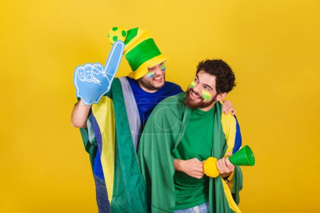 Photo for Two friends, brazilians, soccer fans from brazil, using brazil flag, horn and espupa finger, celebrating victory, screaming Goal. - Royalty Free Image