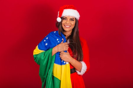 Photo for Beautiful Brazilian woman dressed in Christmas clothes, Santa Claus. with brazil flag. - Royalty Free Image
