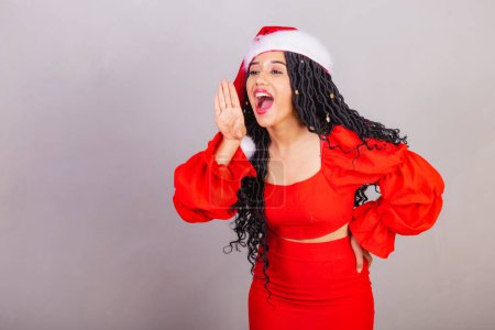 Foto de Mujer negra brasileña, vistiendo ropa de navidad, feliz navidad, sonriendo, gritando promoción, llamando con voz. - Imagen libre de derechos