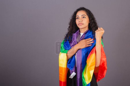 Photo for Young black Brazilian woman, with clenched fist, militancy with LGBT flag, diversity, fight against prejudice. - Royalty Free Image
