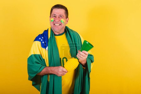 Photo for Adult man, soccer fan from brazil, using flag, with horn making noise. - Royalty Free Image