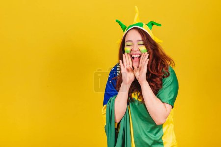 Photo for Caucasian redhead woman brazil soccer fan screaming promotion using hands, publicity photo. - Royalty Free Image