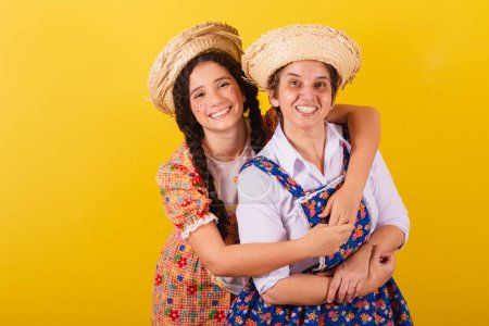 Photo for Grandmother and granddaughter dressed in typical Festa Junina clothes. Hugging and smiling. - Royalty Free Image
