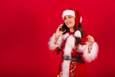 Téléchargez les photos : Femme brésilienne vêtue de vêtements de Noël, le Père Noël. tenant l'appel vocal. - en image libre de droit