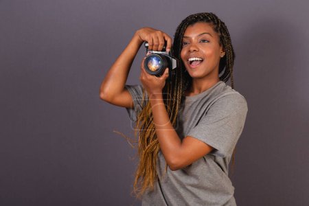 Foto de Joven mujer brasileña afro, fotógrafo, sonriendo, sosteniendo la cámara fotográfica. - Imagen libre de derechos